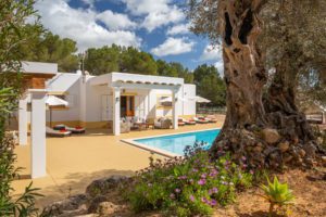 Piscina en villa de Ibiza con tumbonas y dos porches en día soleado