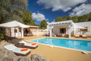 Piscina en villa de Ibiza con tumbonas y dos porches en día soleado 