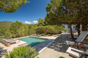Terraza con piscina árboles y hamacas en día soleado en villa Ses Savines de Ibiza