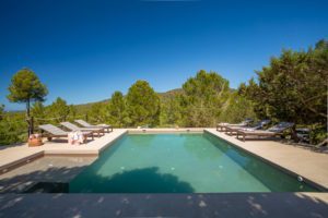 Piscina con hamacas en día soleado en Villa Ses Savines Ibiza