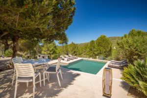 Terraza en día soleado con vistas a la piscina con hamacas en Villa Ses Savines en Ibiza