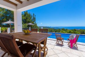 Terraza cubierta con vistas a la piscina y al mar de Ibiza en día soleado