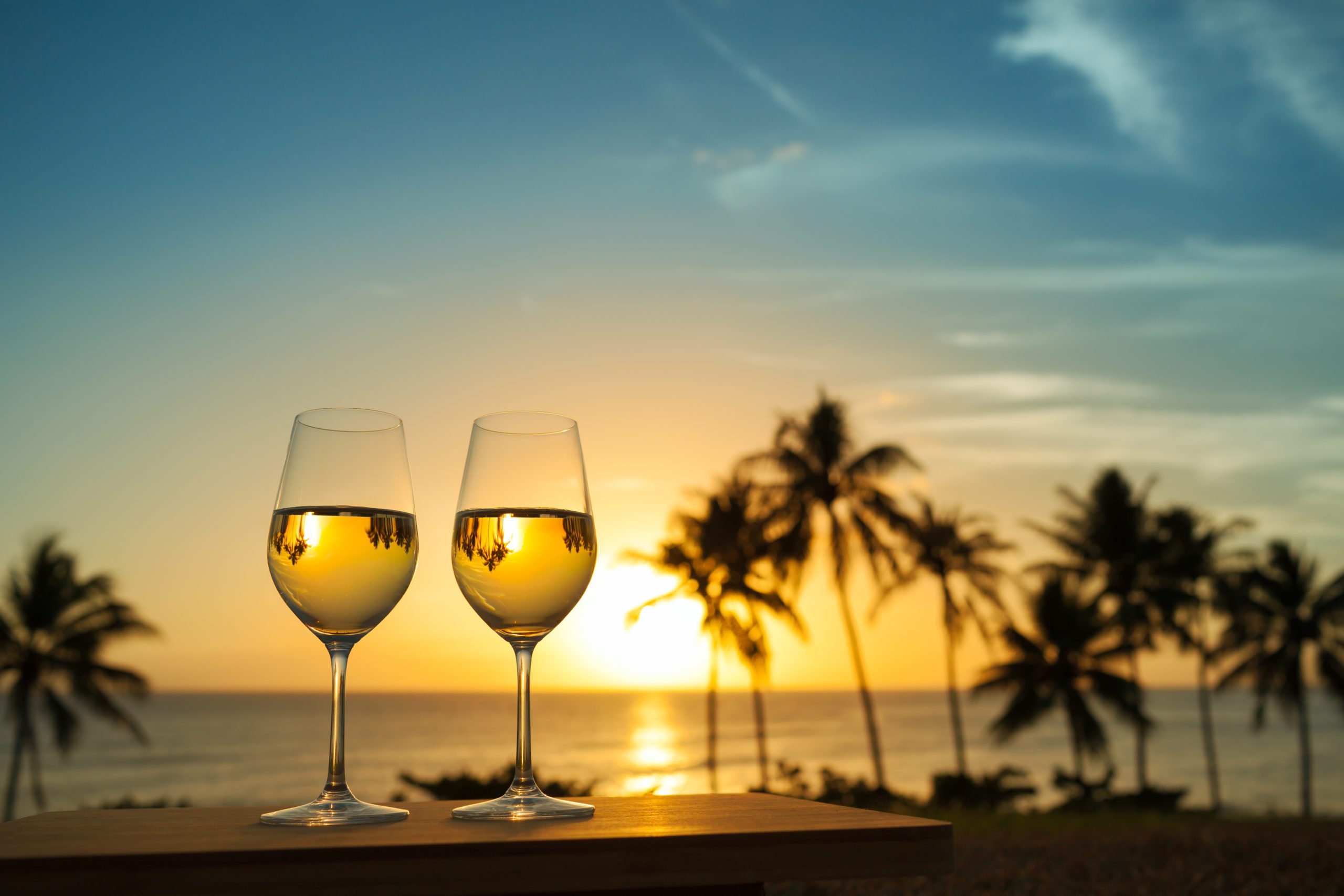 Copas de vino con atardecer de fondo en una playa