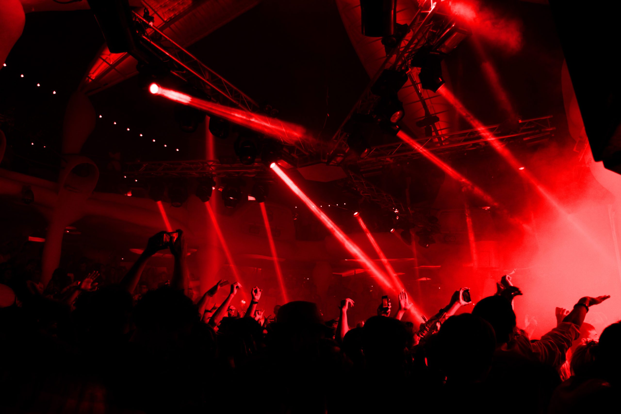 Discoteca llena de gente bailando con luces de neón rojas